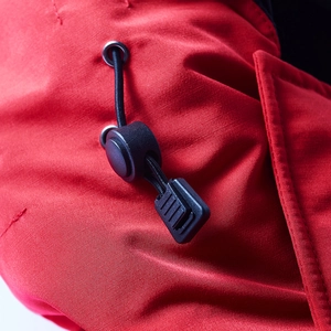 Dettaglio della giacca outdoor rossa con coulisse regolabile e trama del tessuto premium