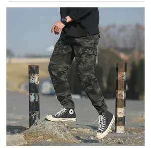 Detail view of cargo pants with camouflage pattern and side pocket on outdoor background
