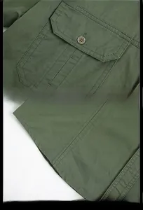 Détail d'une chemise en coton vert armée avec poche à rabat, bouton en métal et ourlet