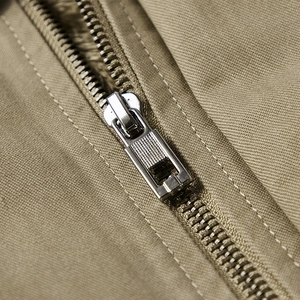 Detailaufnahme von Metallreißverschluss und khakifarbenem Twill-Stoff an der Herrenjacke