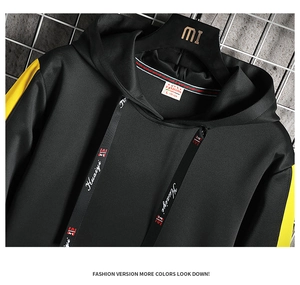 Détail du sweat noir avec bandes jaunes aux manches et cordons à lettres Huaiyi blanches