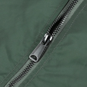 Detailed close-up of a durable black plastic zipper on a dark green bomber jacket