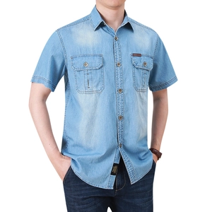 Detail of light blue denim shirt with outdoor leather tag and metal buttons on chest pockets