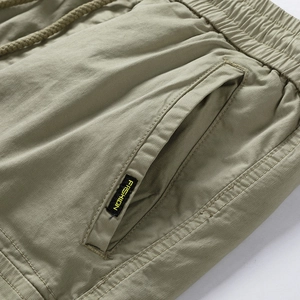 Detail of cargo shorts showing elastic drawstring waist and fashion label on olive twill