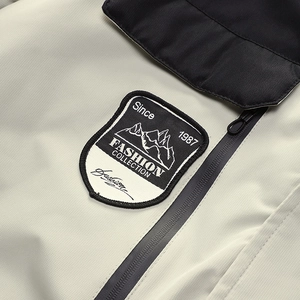 Detail eines bestickten Berg-Patches und schwarzen Reißverschlusses an der Winterjacke