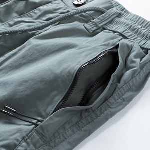 Detailed close-up of greyish-green cotton cargo shorts with zipper pocket and drawstring waist