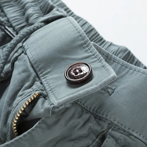 Detail view of cotton cargo shorts featuring drawstring waist, metal zipper, and resin button