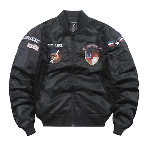 Dettaglio di un giubbotto bomber nero con toppe ricamate vintage e tasca con zip