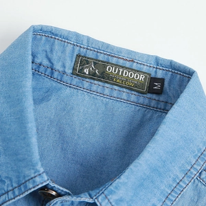 Macro shot of blue denim shirt collar with outdoor woven label and precision stitching