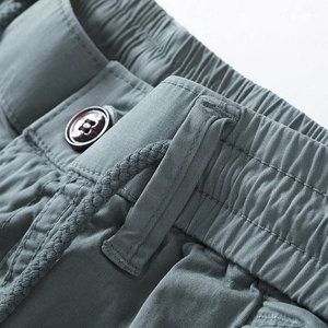 Detail of grey-green cotton cargo shorts with elastic waist and woven drawstring