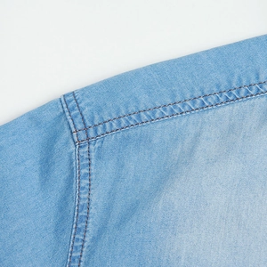 Detailed close-up showing reinforced double-needle brown stitching on light blue denim fabric