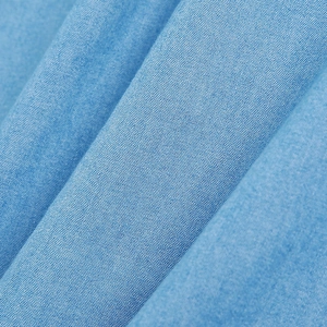 Close-up of light blue cotton denim fabric texture showing fine weaving and fiber detail
