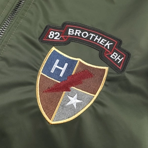 Dettaglio del bomber verde militare che mostra il ricamo di qualità e la trama del tessuto