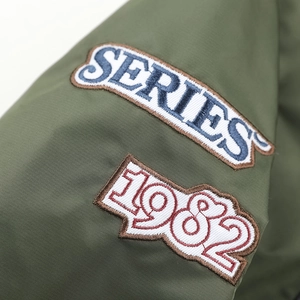 Dettaglio del bomber verde militare con toppe ricamate Series 1982 su tessuto tecnico