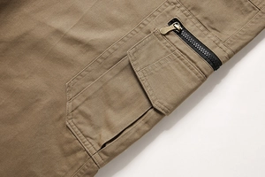 Detail der khakifarbenen Cargo-Hose mit 3D-Klapptasche und schwarzem Reißverschluss aus Baumwolle
