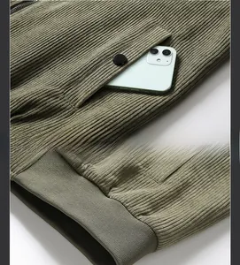 Detail of olive green corduroy jacket showing side pocket and ribbed elastic hem