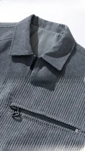 Detail view of grey corduroy jacket featuring a classic collar and zip pocket design