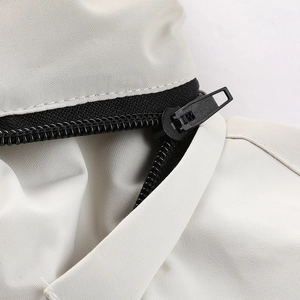 Detail des schwarzen Reißverschlusses auf dem beigen Windbreaker-Jackenstoff