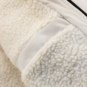 Nahaufnahme von beigem Fleece-Stoff und glatter Textur mit schwarzem Metallreißverschluss