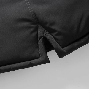 Dettaglio dell'orlo del cappotto invernale nero da uomo con cuciture e spacco laterale