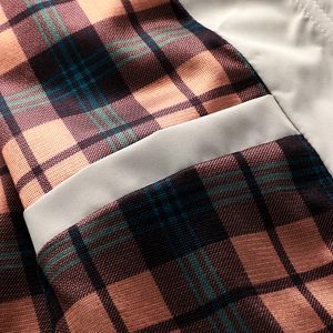 Detail of waterproof outdoor jacket featuring multi-color plaid and beige fabric stitching