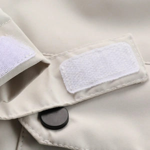 Detail der beigefarbenen Jackenmanschette mit weißem Klettverschluss und Knopfstruktur