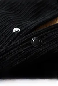 Macro view of glossy round buttons on black ribbed corduroy fabric for casual jacket