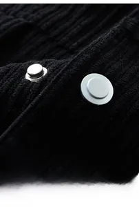 Close-up of silver metal buttons and ribbed texture on a black corduroy jacket