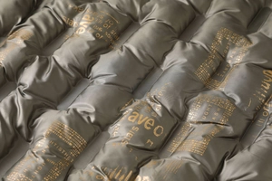 Detail of quilted waterproof fabric with metallic gray finish and golden graphic print