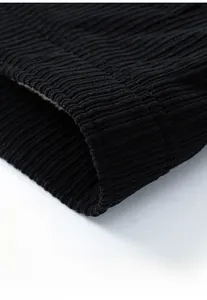 Macro shot of the ribbed hem on a black corduroy jacket showing high quality stitching