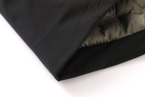 Detailed close-up of heavy padded jacket showing black windproof shell and olive quilted lining