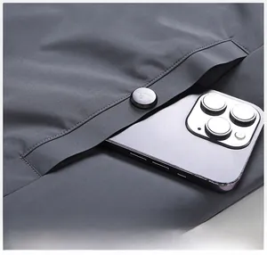 Detail view of large coat pocket with matte button closure showing smartphone storage capacity