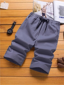 Graue Herren-Freizeitshorts mit Kordelzug und Taschen auf rustikalem Holzhintergrund