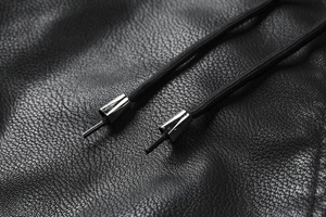 Detail of black faux leather texture with metal drawstring tips on men's winter jacket