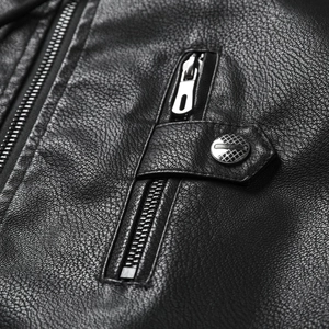 Detail of black pebbled leather texture with silver metal zipper and decorative snap button