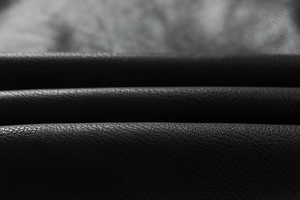Macro shot of black pebbled faux leather texture on mens winter hooded motorcycle jacket