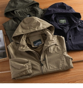 Detail of hooded windbreakers with zipper pockets and breathable mesh lining on wood surface