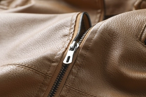 Detail of premium brown faux leather texture with silver metal zipper and fine stitching