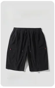 Detail of black breathable corduroy shorts with elastic drawstring waist and red side tag