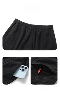 Detail of elastic drawstring waist and side zip pocket on black corduroy shorts