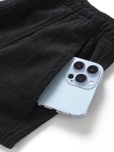 Black corduroy shorts with elastic waist and deep side pocket holding a smartphone