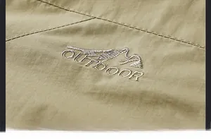 Close-up of mountain embroidery and outdoor lettering on khaki windbreaker jacket