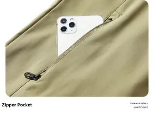 Detail der verdeckten Reißverschlusstasche an der grünen Softshelljacke mit Handy