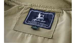 Close-up of olive green flight jacket showing ribbed collar detail and brand woven label