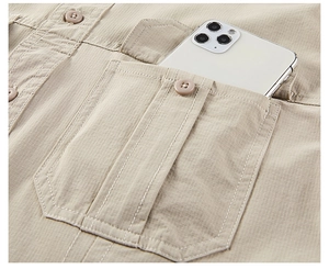 Detail of khaki cargo shirt pocket showing ripstop fabric texture and a large smartphone