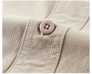 Close-up of khaki textured fabric with four-hole button and double stitching on shirt