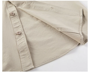 Detail of light khaki shirt showing rounded hem and high-quality stitching on fabric
