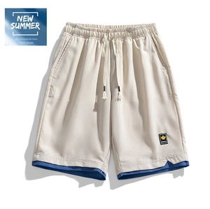 Detail of men's beige summer shorts featuring drawstring waist and blue layered hem
