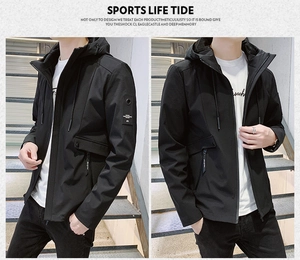 Detail of black hooded windbreaker jacket with sleeve patch and zipper pockets