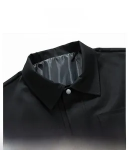 Detailed close-up of a black twill jacket collar with a premium matte grey snap button